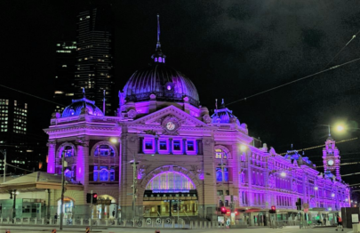 Flinders St Station in Melbourne lit by purple lights.